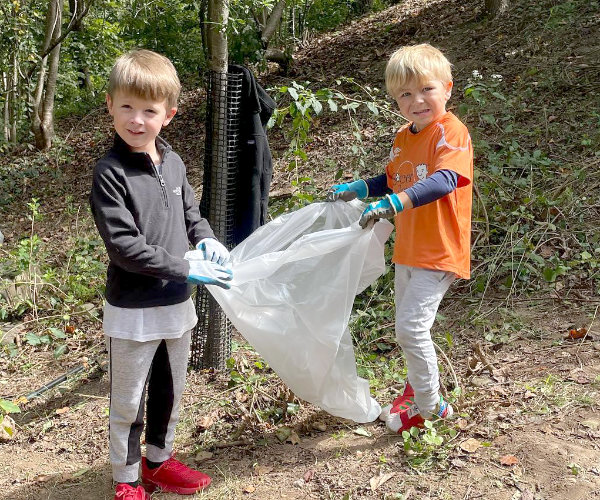 Two children bagging trash from inside the park.