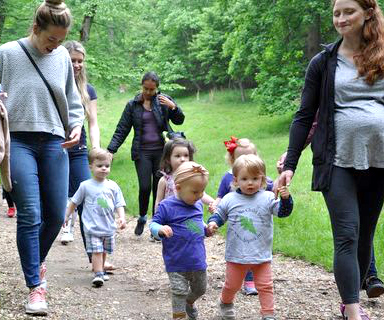 Happy toddlers walking down a path with their parents.