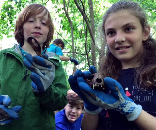 Two children holding and looking at animal bones.